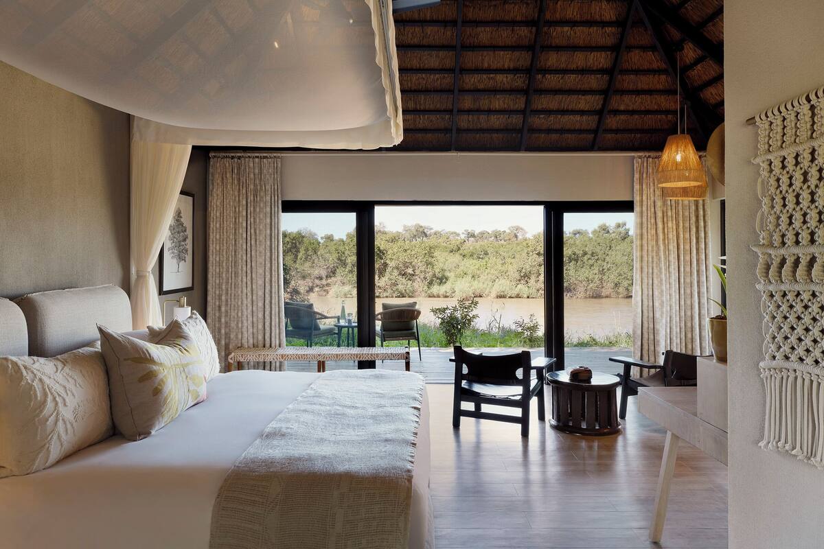Een slaapkamer met een groot bed, een eettafel, stoelen en uitzicht op de omgeving.