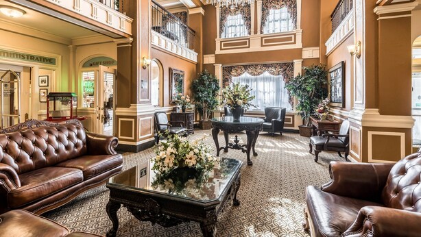A spacious lobby with a high ceiling, ornate chandeliers, and classic furniture.