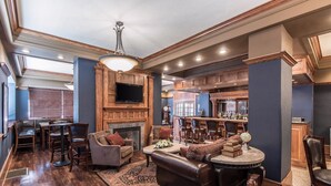 A spacious living room with a fireplace, a dining area, and a bar area with wooden cabinets and a television.