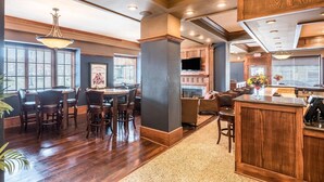 A spacious kitchen with wooden cabinets, a dining area with a round table and chairs, and a bar area with stools.