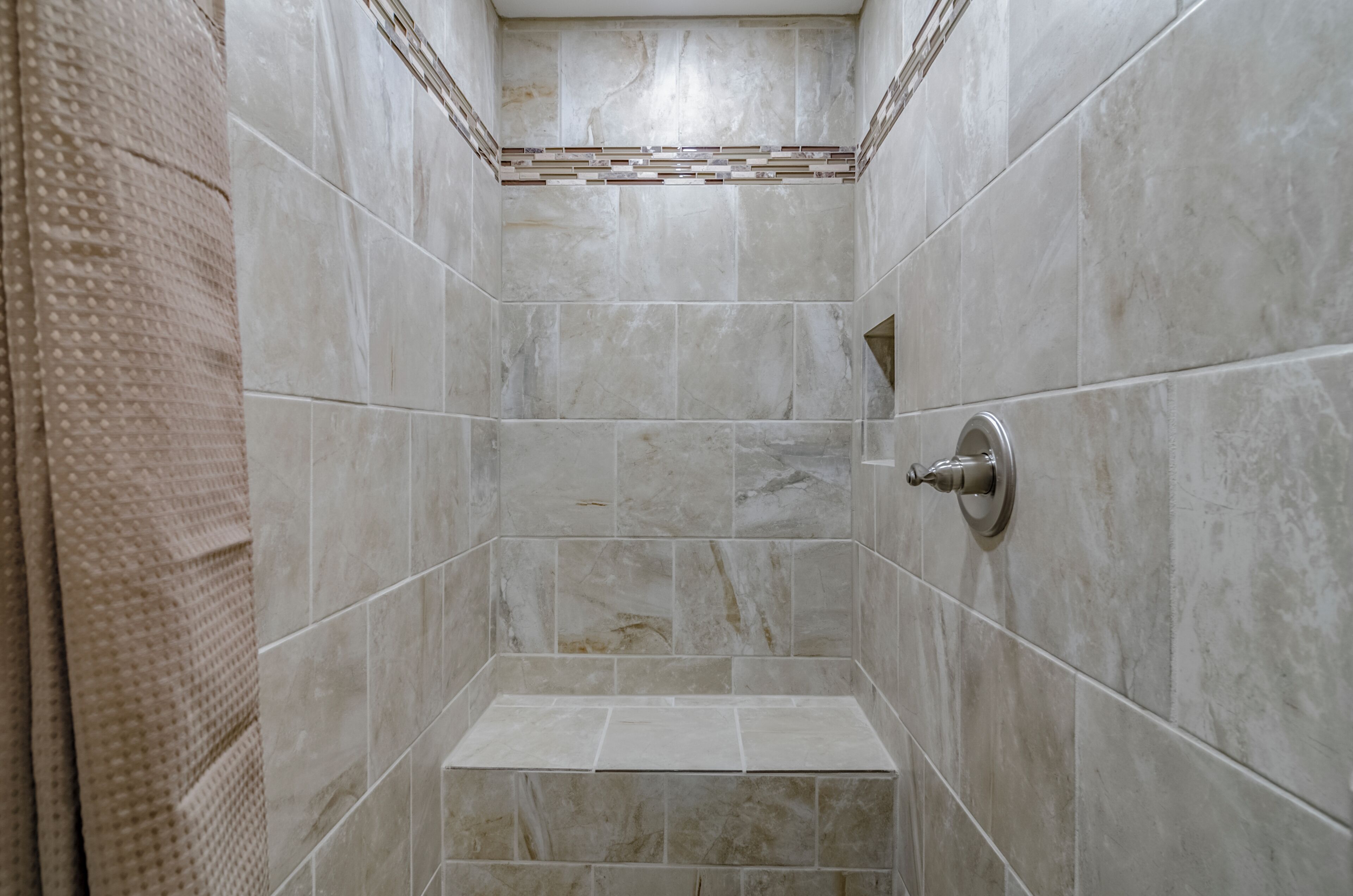 Un espacio de ducha con paredes de azulejos y un cabezal.