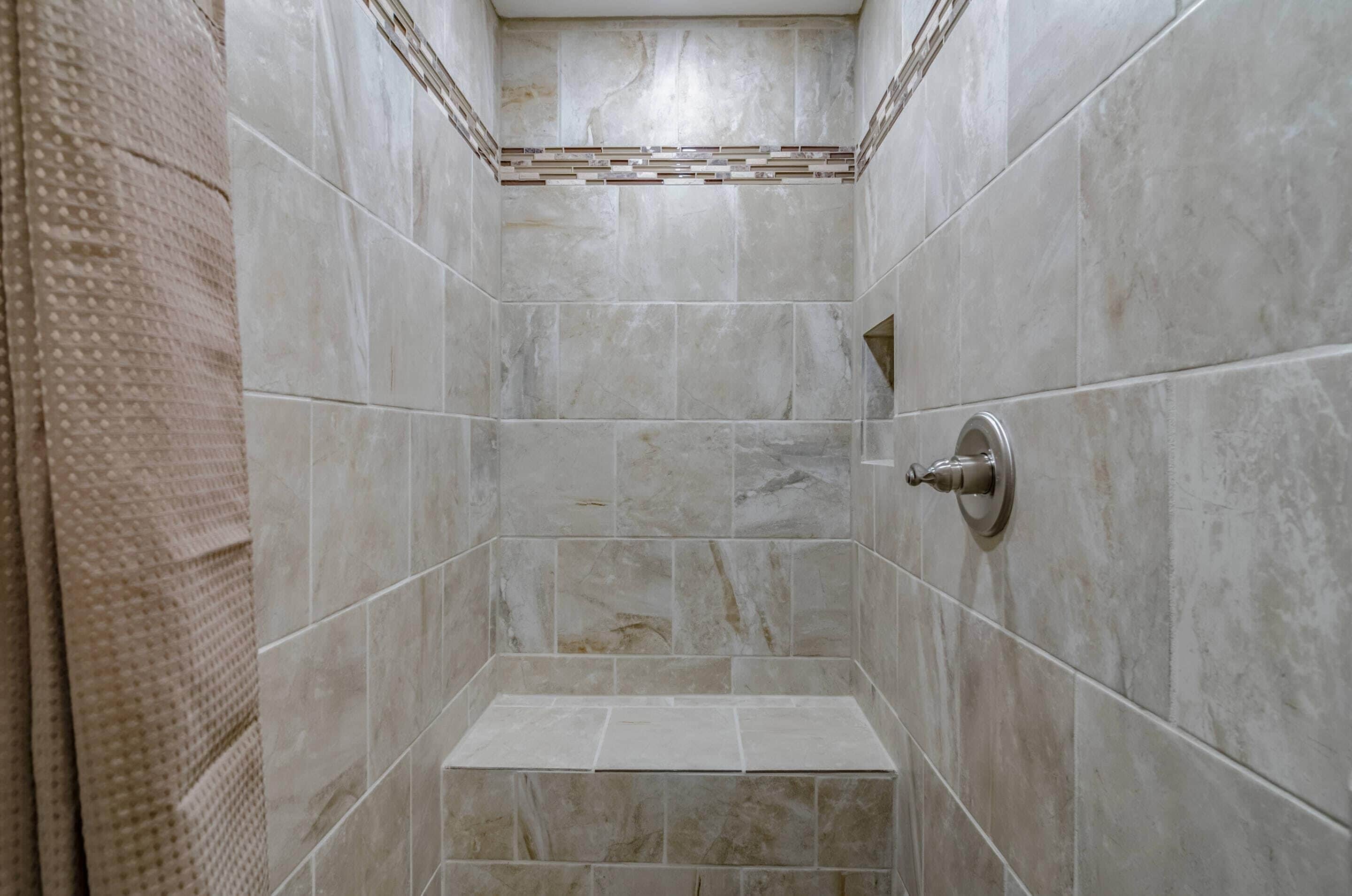 Un espacio de ducha con paredes de azulejos y un cabezal.