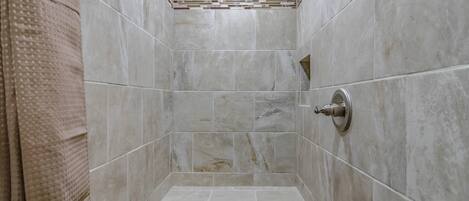 Un espacio de ducha con paredes de azulejos y un cabezal.