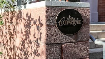A brick wall with a circular sign that reads "The Conwell Inn."