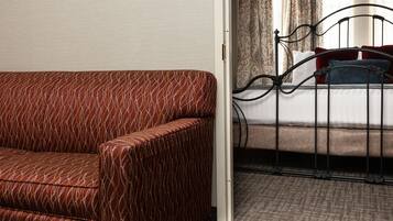 A hotel room with a patterned sofa, a metal bed frame, and a patterned carpet.