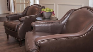 Two brown leather armchairs with a metal bowl and apples on a small round table. - The Conwell Inn (Philadelphia)