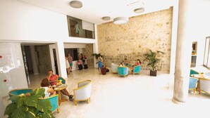 A spacious lobby with a high ceiling, stone wall, and modern seating areas. - Hotel Amic Gala (Palma de Mallorca)