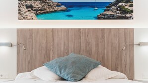 A bedroom with a wooden headboard, a bed with white linens, and a blue pillow. - Hotel Amic Gala (Palma de Mallorca)