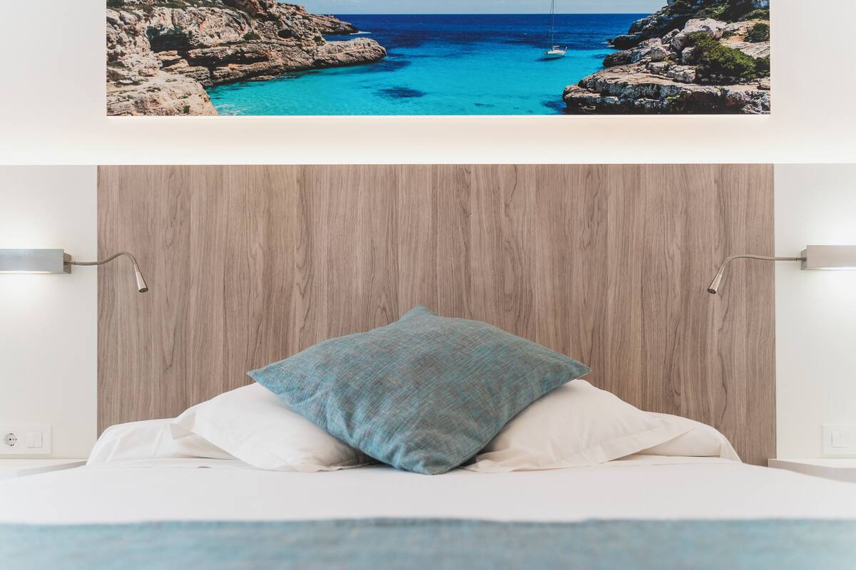 A bedroom with a wooden headboard, a bed with white linens, and a blue pillow.