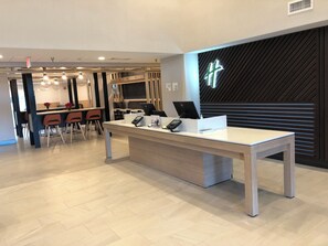 Mostrador de recepción con una computadora portátil, un teléfono y una caja pequeña, probablemente para el registro de huéspedes.