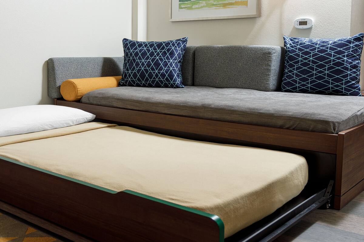 A convertible sofa bed with a wooden frame and a mattress.