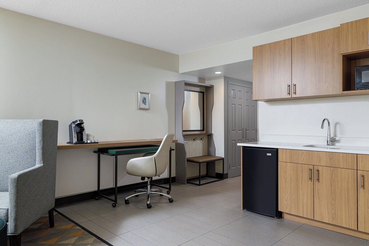 A compact kitchen with a sink, microwave, and wooden cabinets.