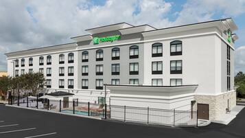 A Holiday Inn hotel with a modern facade, multiple windows, and a gated parking area.