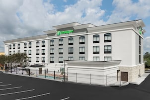 A Holiday Inn hotel with a modern facade, multiple windows, and a gated parking area.