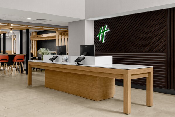 A reception desk with a modern design, featuring a wooden table and a black counter. - Holiday Inn Cleveland by IHG (Cleveland)