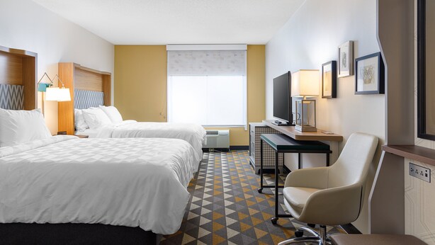 A hotel room with two beds, a desk with a chair, a television, and a window with blinds. - Holiday Inn Cleveland by IHG (Cleveland)