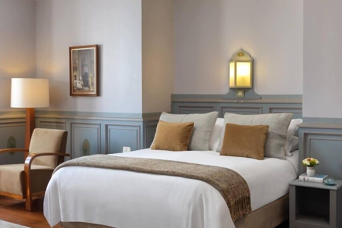 A neatly arranged bedroom with a large bed, bedside tables, a chair, and a lamp.