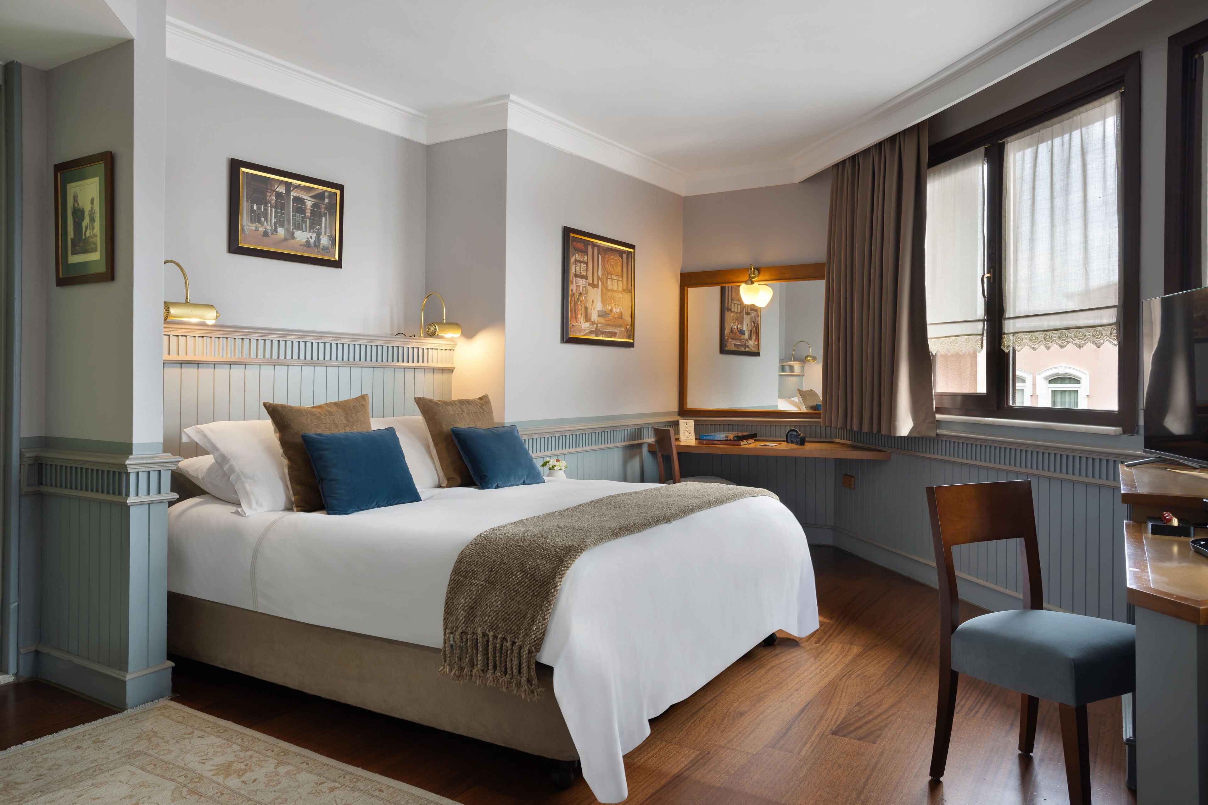 Een netjes ingerichte slaapkamer met een groot bed, een nachtkastje, een stoel en een raam met gordijnen.