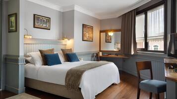 Een netjes ingerichte slaapkamer met een groot bed, een nachtkastje, een stoel en een raam met gordijnen.