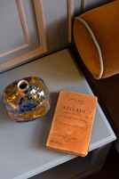 Un libro con el título 'AZIYADÉ' y un florero de vidrio decorativo sobre una mesa.