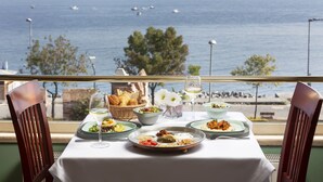 A table set with various dishes and a glass of wine, overlooking a body of water with boats. - Armada Istanbul Old City Hotel (Istanbul)