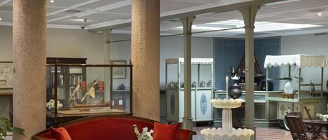 Un hall amplio con una fuente central, un sofá rojo y una exhibición de antigüedades.