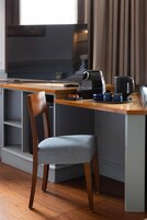 Una habitación moderna con un escritorio de madera, una silla, un televisor y una cafetera.