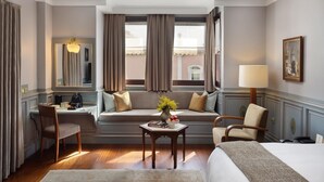 A hotel room with a bed, a desk, a chair, a sofa, a small table with a vase of flowers, and a lamp. - Armada Istanbul Old City Hotel (Istanbul)
