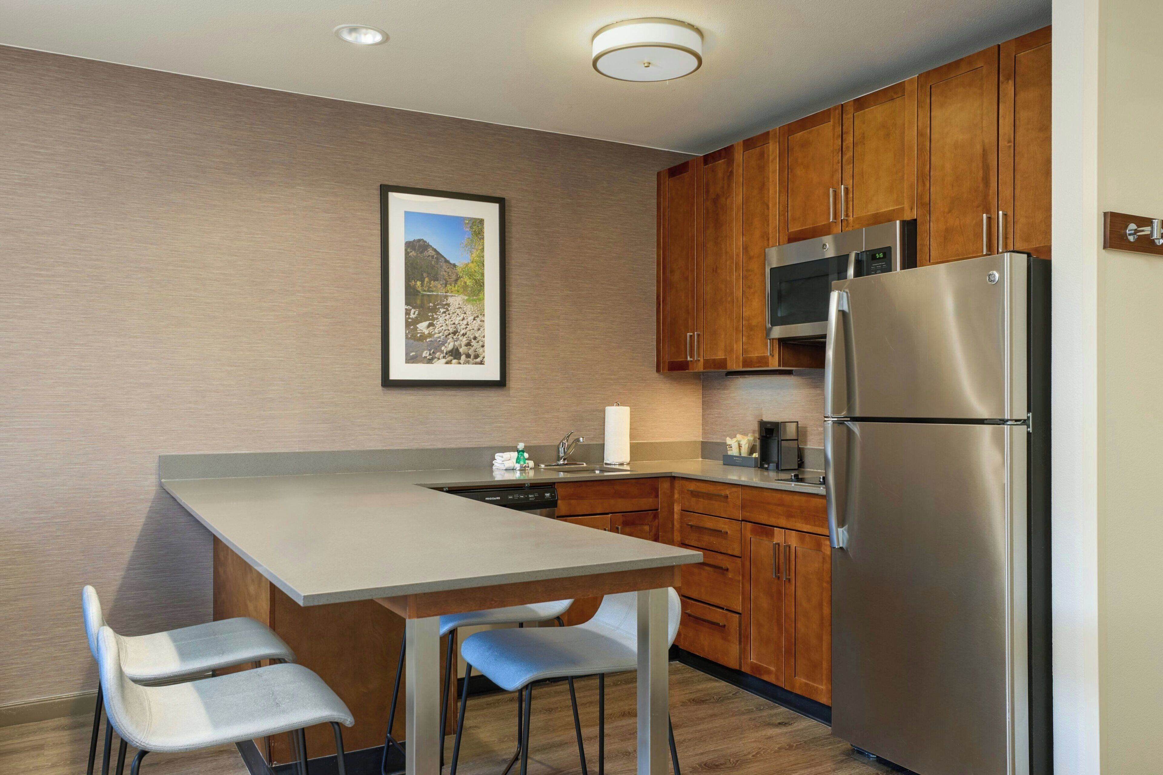 A modern kitchen with wooden cabinets, a stainless steel refrigerator, and a built-in dishwasher.