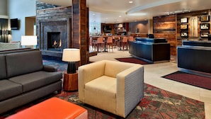 A hotel lobby with a fireplace, seating area, bar, and reception desk.
