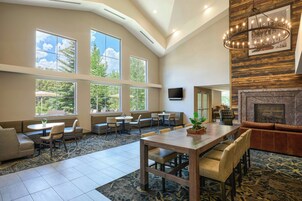 A spacious indoor area with multiple seating arrangements, large windows, and a fireplace.
