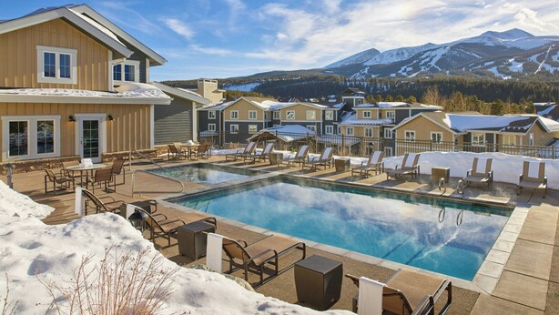 A pool area with lounge chairs and a view of snow-covered mountains.