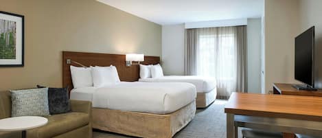 A hotel room with a bed, a sofa, a TV, and a desk.