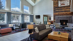 A spacious living room with a fireplace, large windows, and modern furniture.