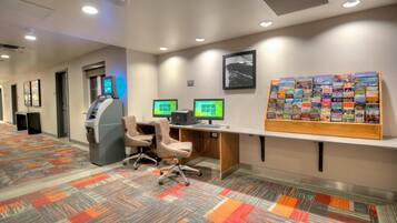 A hotel reception area with an ATM, computers, and a display of travel brochures.