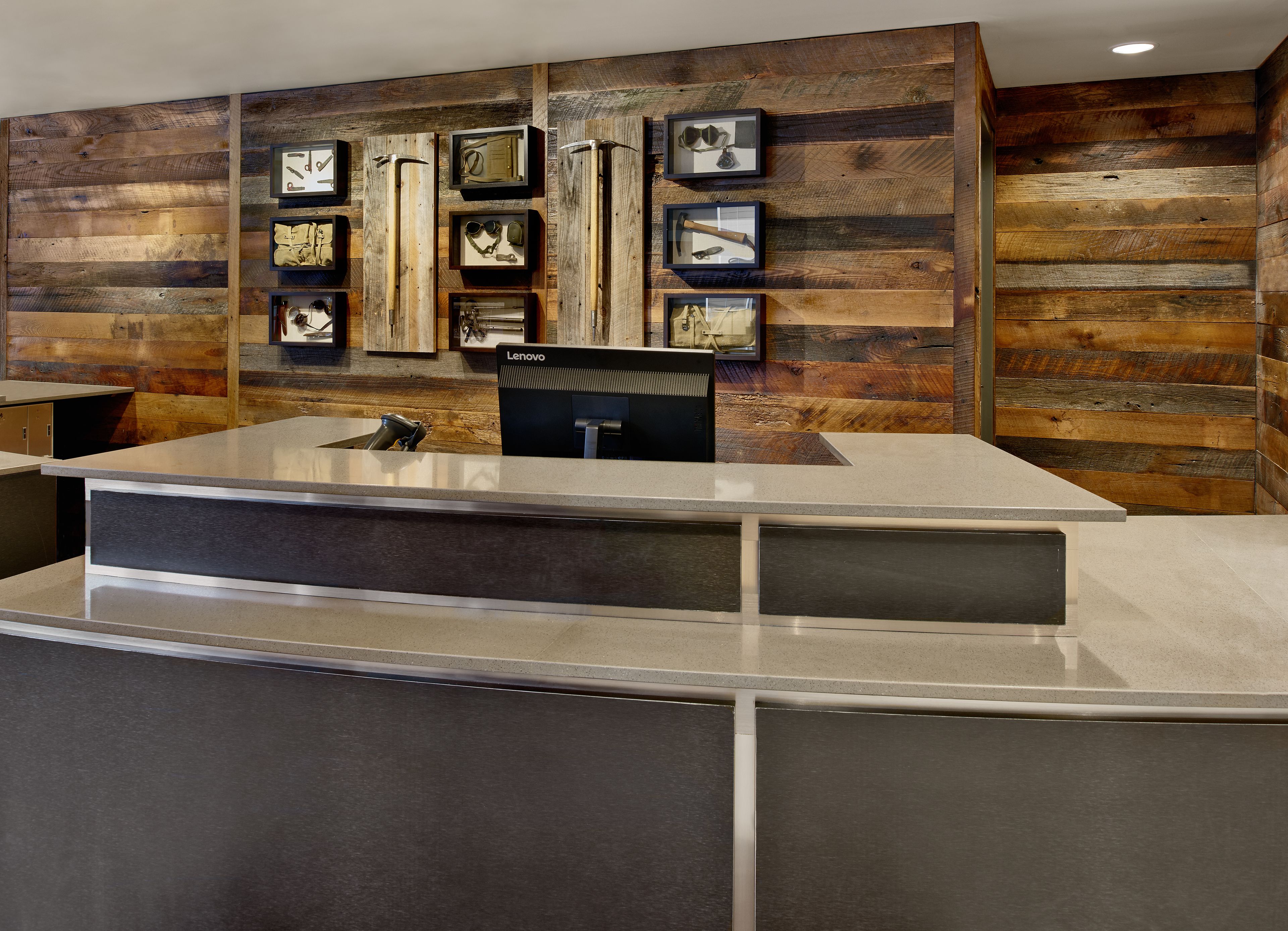 Un mostrador de recepción de diseño moderno, paneles de madera en las paredes y objetos enmarcados sobre el mostrador.