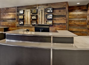 A reception desk with a modern design, wooden paneling on the walls, and framed items above the counter. - Residence Inn by Marriott Breckenridge (Breckenridge)