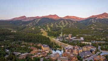 A mountainous town with a central road leading to a lake, surrounded by dense forests and mountains.