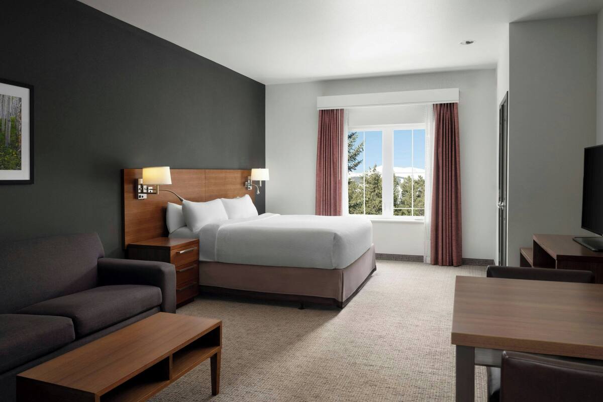 Une chambre d’hôtel avec un lit, un canapé, un bureau et une télévision.