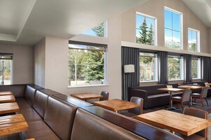 A modern interior with a long bench seating area, tables, and a sofa.