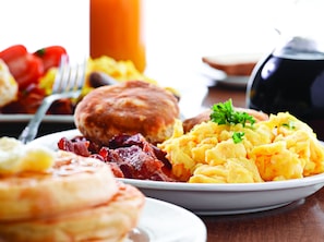 A breakfast plate with pancakes, bacon, scrambled eggs, and toast.