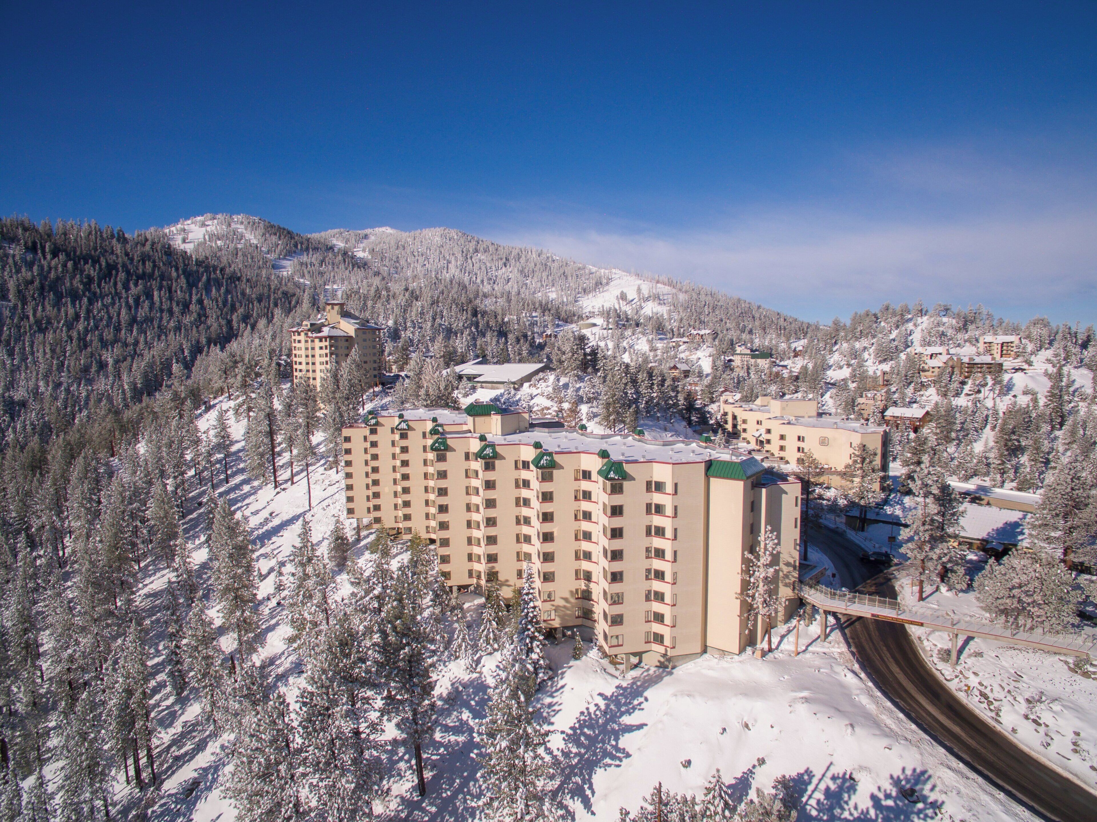 A multi-story hotel with a ski lift in a snowy mountainous area.