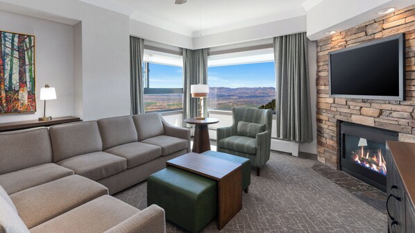 A hotel room with a sofa, armchair, table, fireplace, and a large TV. - Holiday Inn Club Vacations Tahoe Ridge Resort by IHG (Stateline)