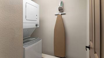 Une buanderie équipée d’un lave-linge, d’un sèche-linge et d’une planche à repasser.