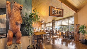 Interior de restaurant amb decoració de fusta, un rètol que diu 'BISTRO' i una escultura d'ós.
