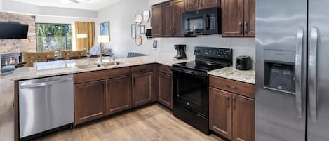 Una cocina moderna con armarios de madera oscura, electrodomésticos de acero inoxidable, encimera de granito y lavavajillas integrado.