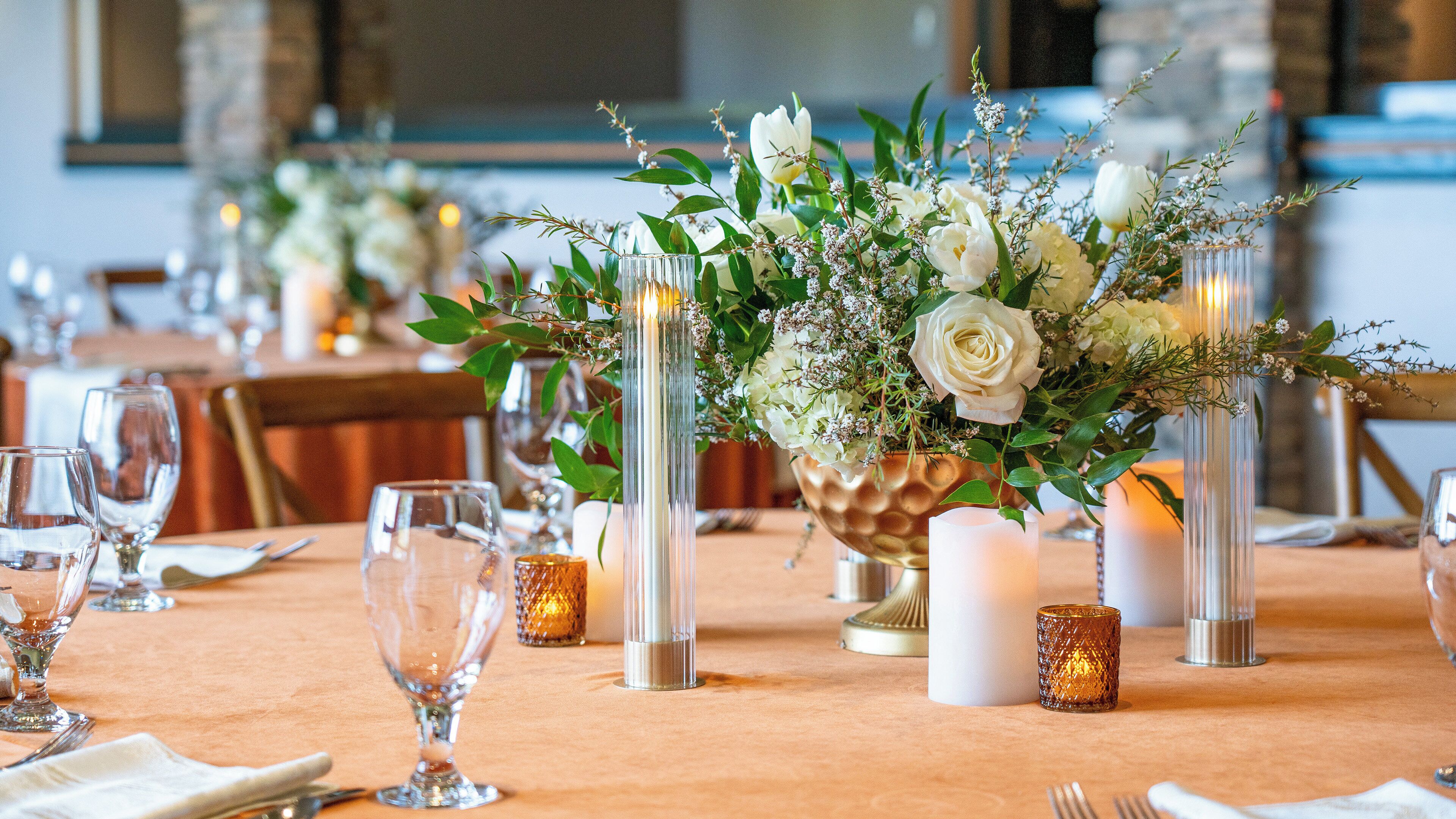 A table set with clear glassware, candles, and floral arrangements.