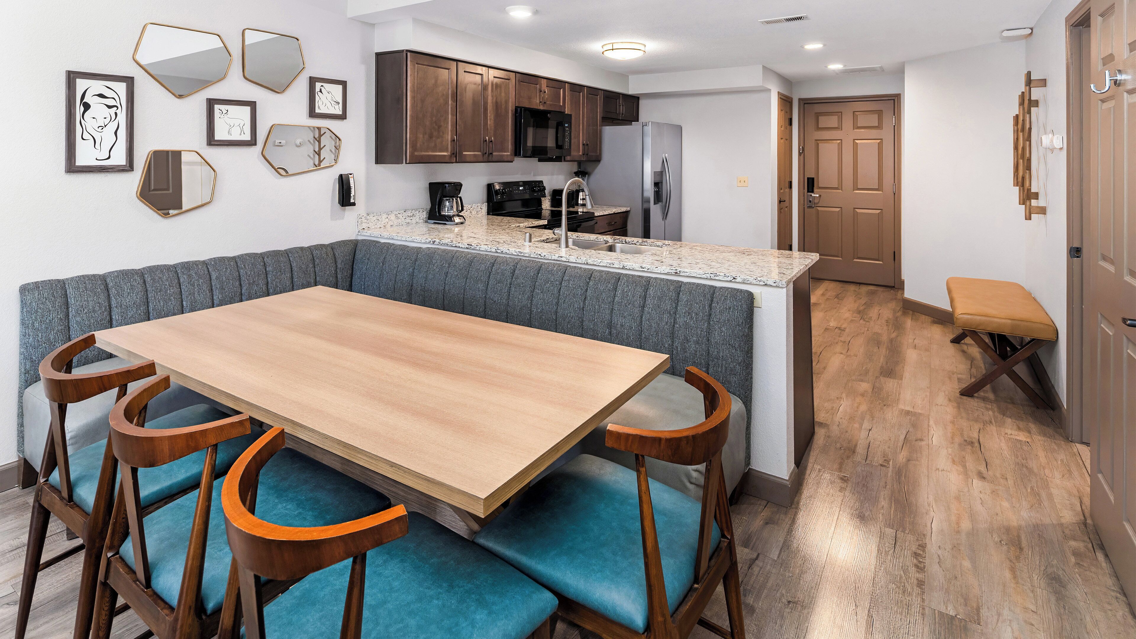 A modern kitchen with a central island, wooden chairs, and a dining table.