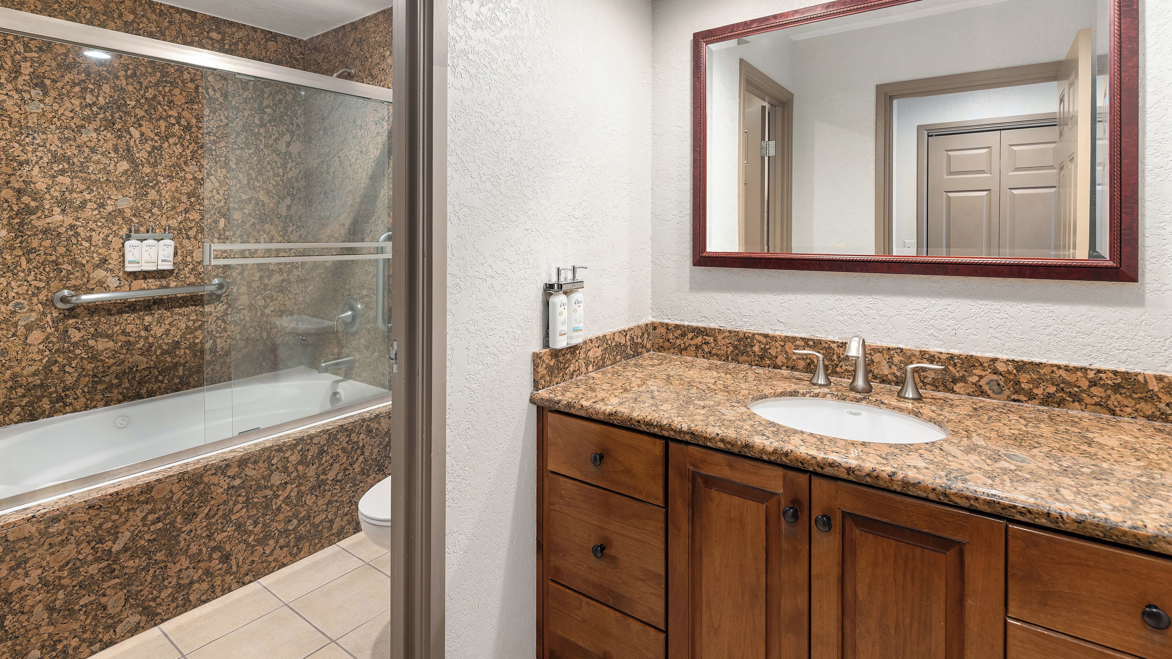 A bathroom with a shower, a sink, and wooden cabinets.