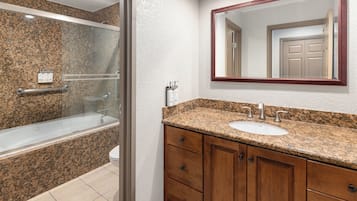 A bathroom with a shower, a sink, and wooden cabinets.